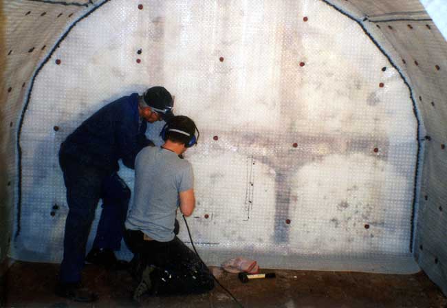 Andrews's sons drill the end cellar wall and  hammer in the plastic plugs.